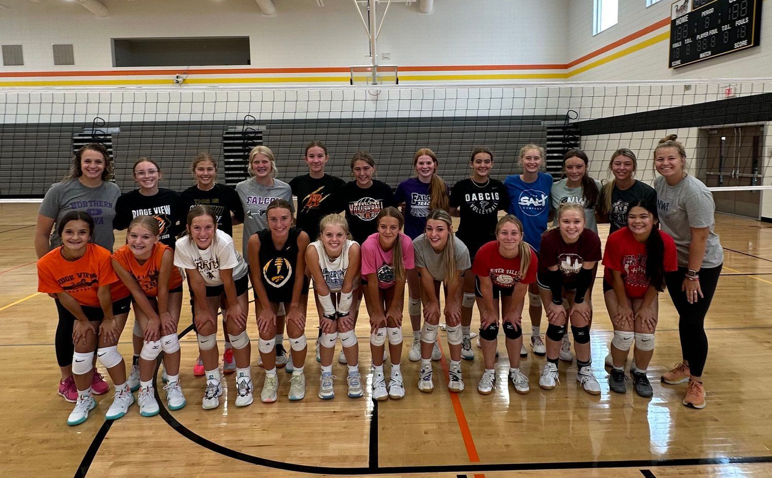 A group of volleyball players are posing for a picture in a gym.
