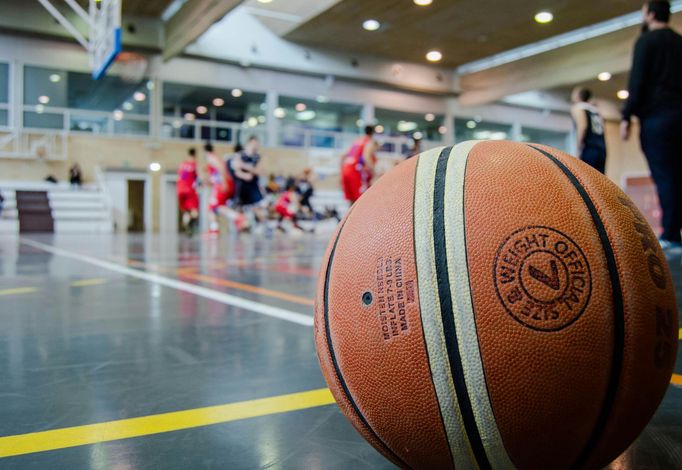 A basketball is sitting on the floor of a basketball court.