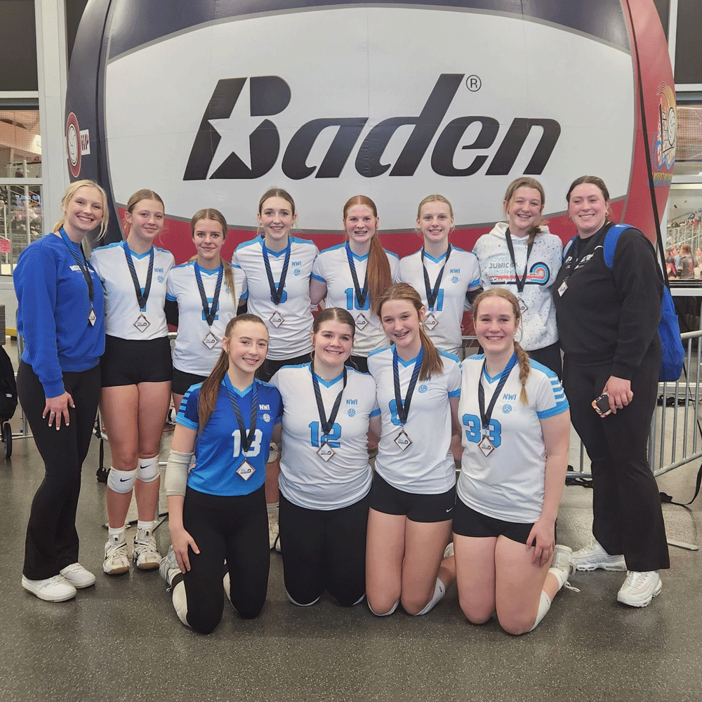 A group of girls are posing for a picture in front of a baden sign