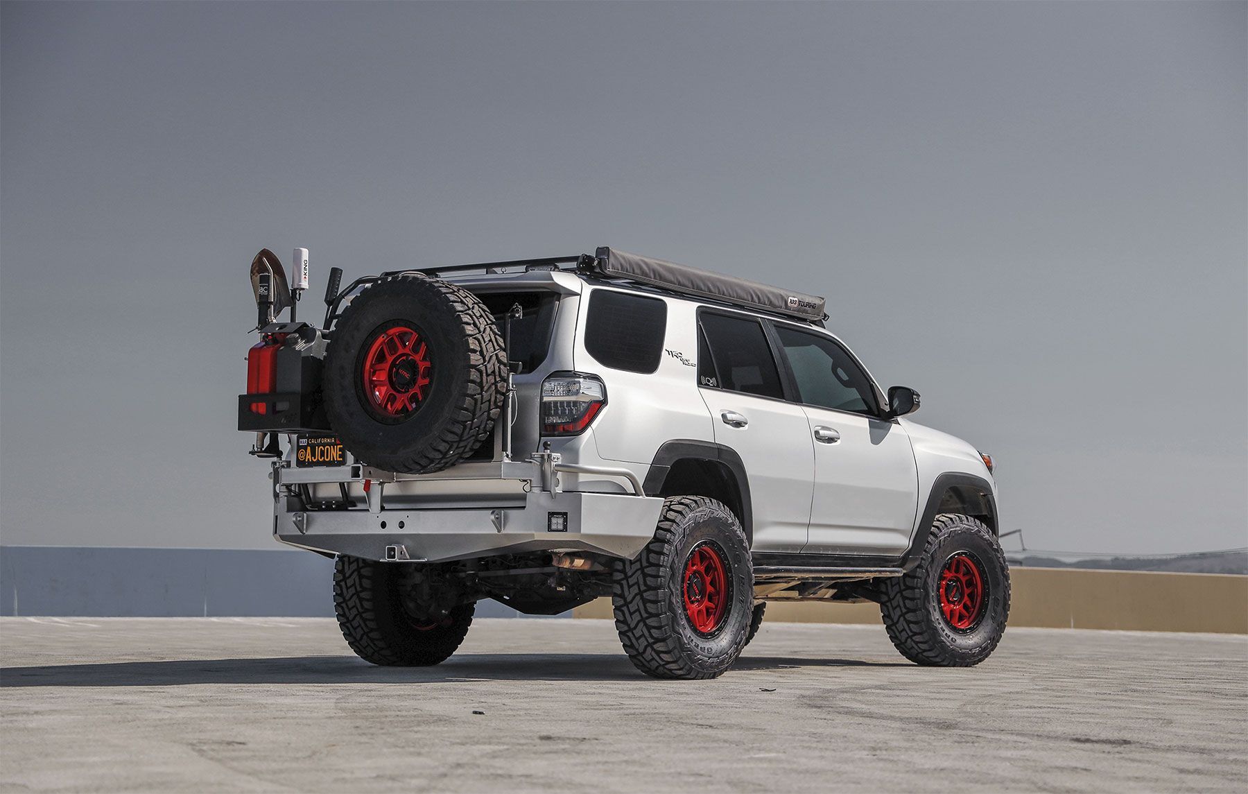 A white suv with red wheels is parked on a beach
