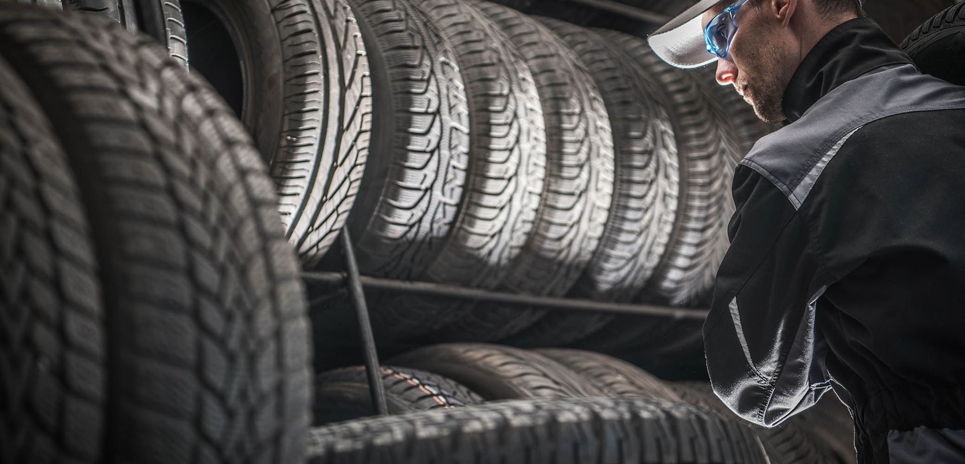 A man is looking at a stack of tires in a garage.