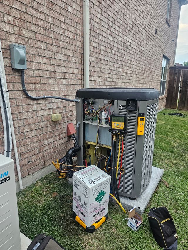 Open electrical panel beside brick wall with wiring and tools on the ground