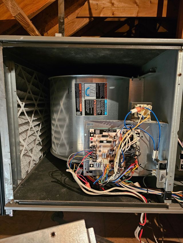 Open HVAC unit with exposed wiring and control boards inside a metal cabinet