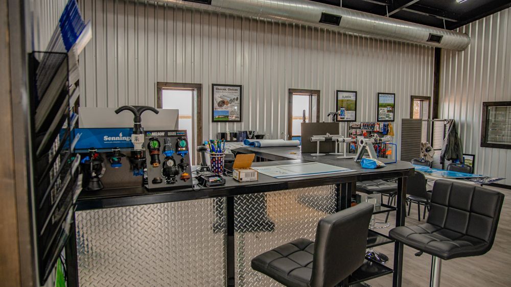 A workshop featuring a metal workbench with equipment, two chairs, and wall art in a room with corrugated metal walls.