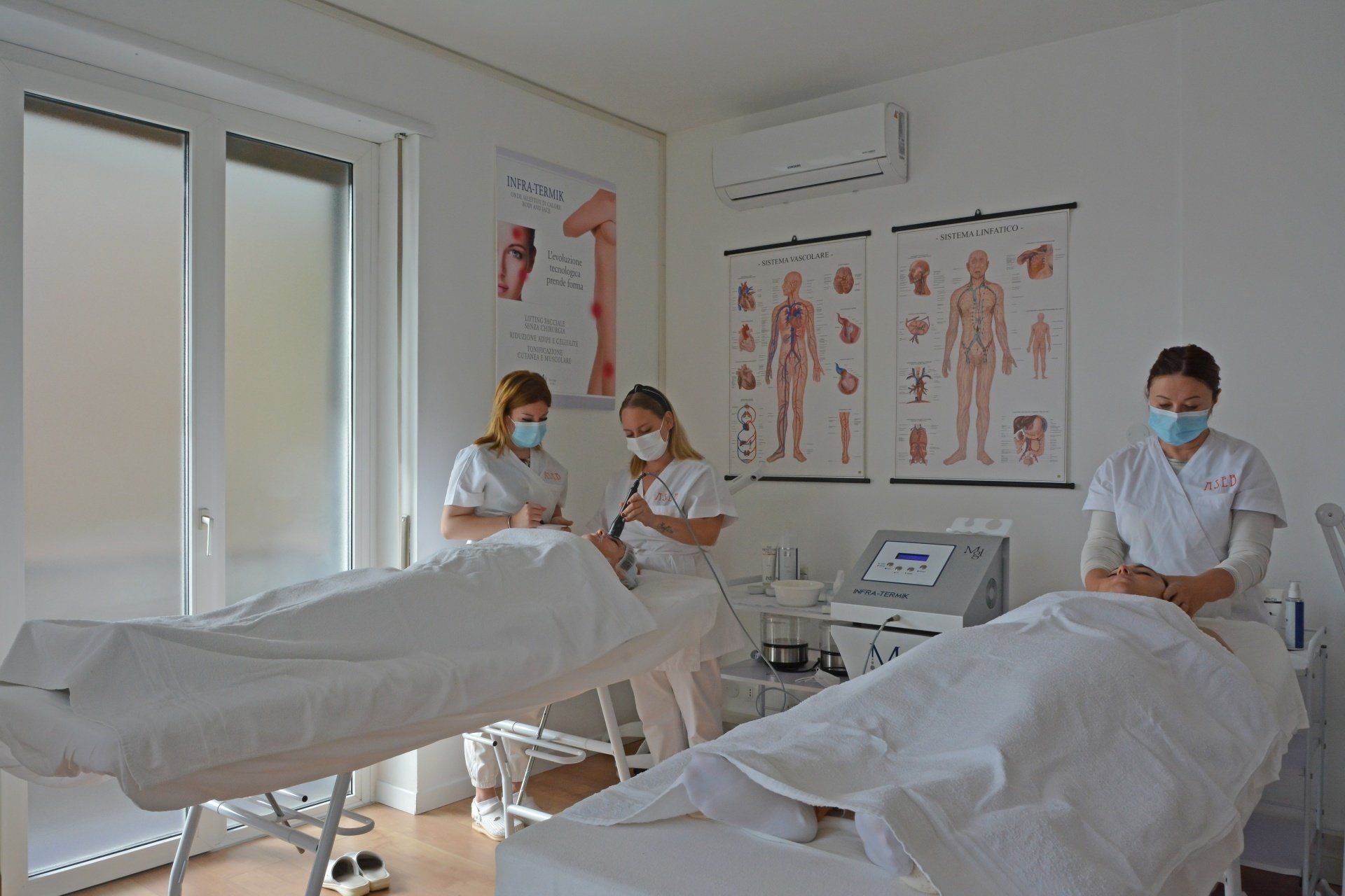 Due operatori sanitari con la mascherina si prendono cura dei pazienti sui lettini di una clinica.