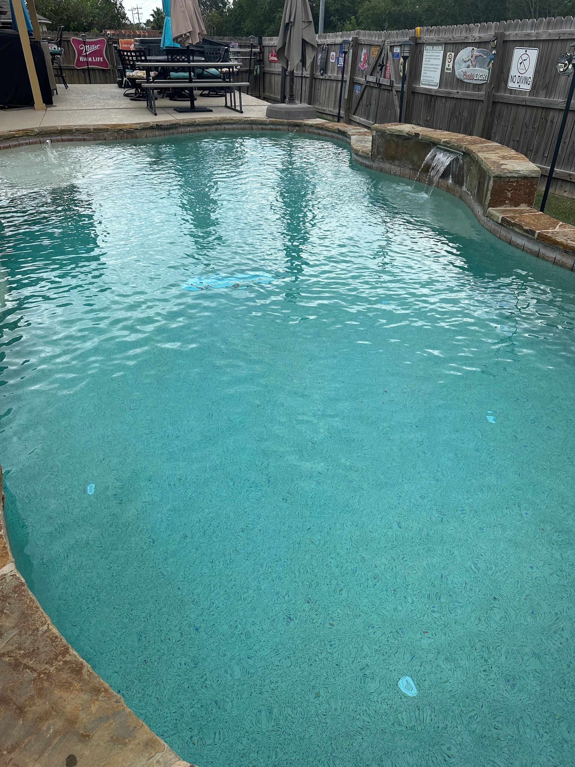 Turquoise resort pool with stone edge and lounge chairs in the background