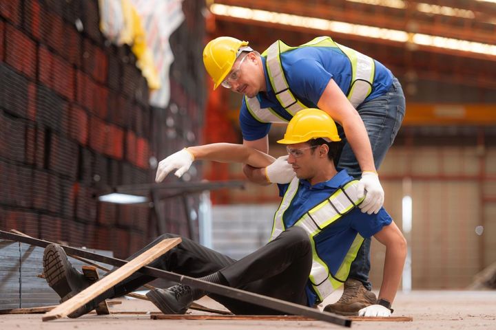 Two construction workers in hard hats inspecting debris at a worksite