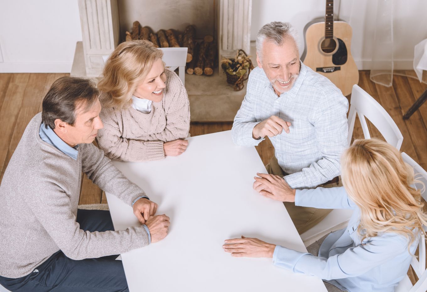 Four people in a bright room sit around a white table in a discussion.