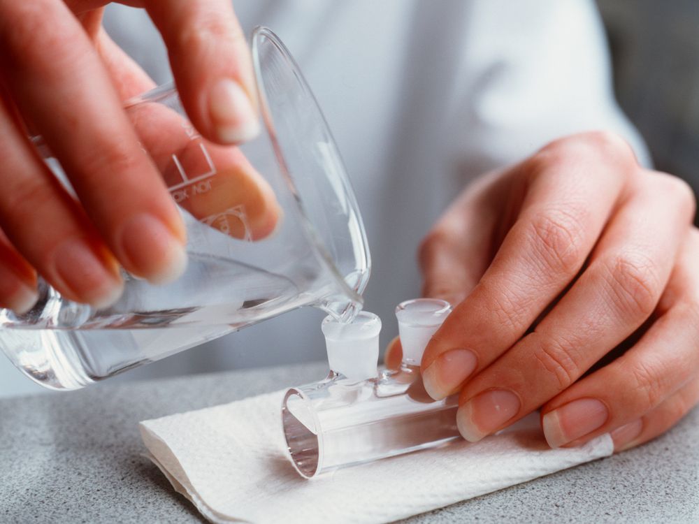 A person is pouring liquid from a beaker into a test tube