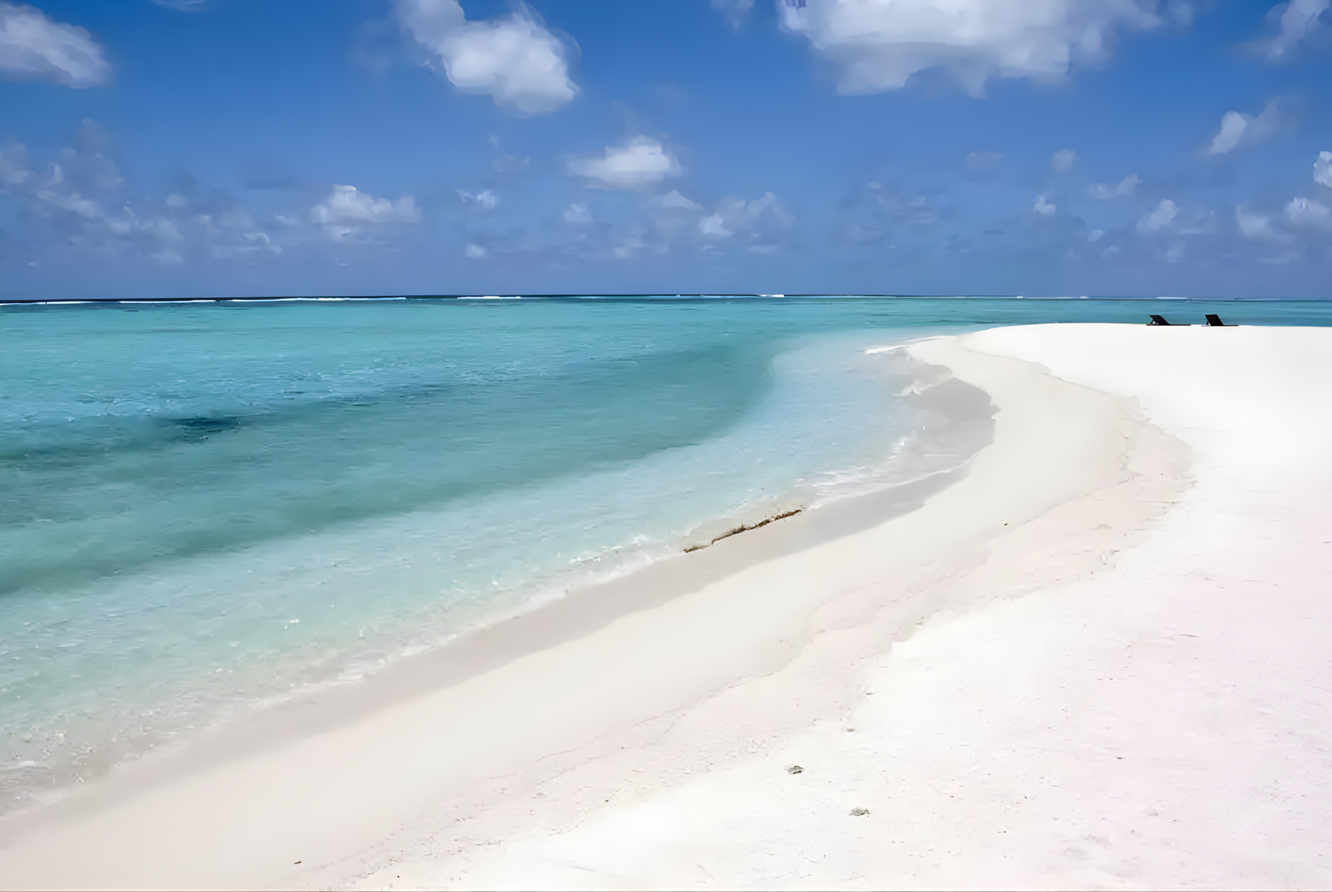 White sandy tropical beach with turquoise water, gentle waves, and a bright blue sky with clouds in Abu Dhabi.