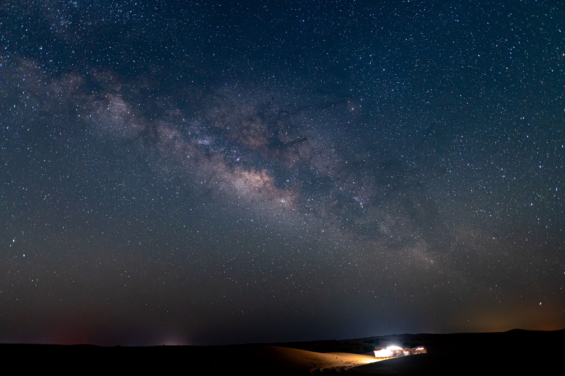 Starry night sky with the Milky Way over a dark landscape in Al Quaa.