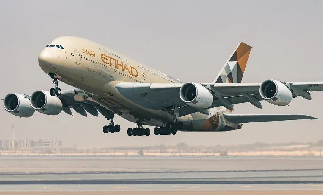 Etihad Airways A380 landing, with landing gear down over a runway in hazy light