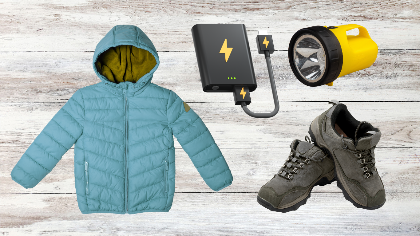 Blue puffer jacket, hiking boots, flashlight, and power bank on a white wood background
