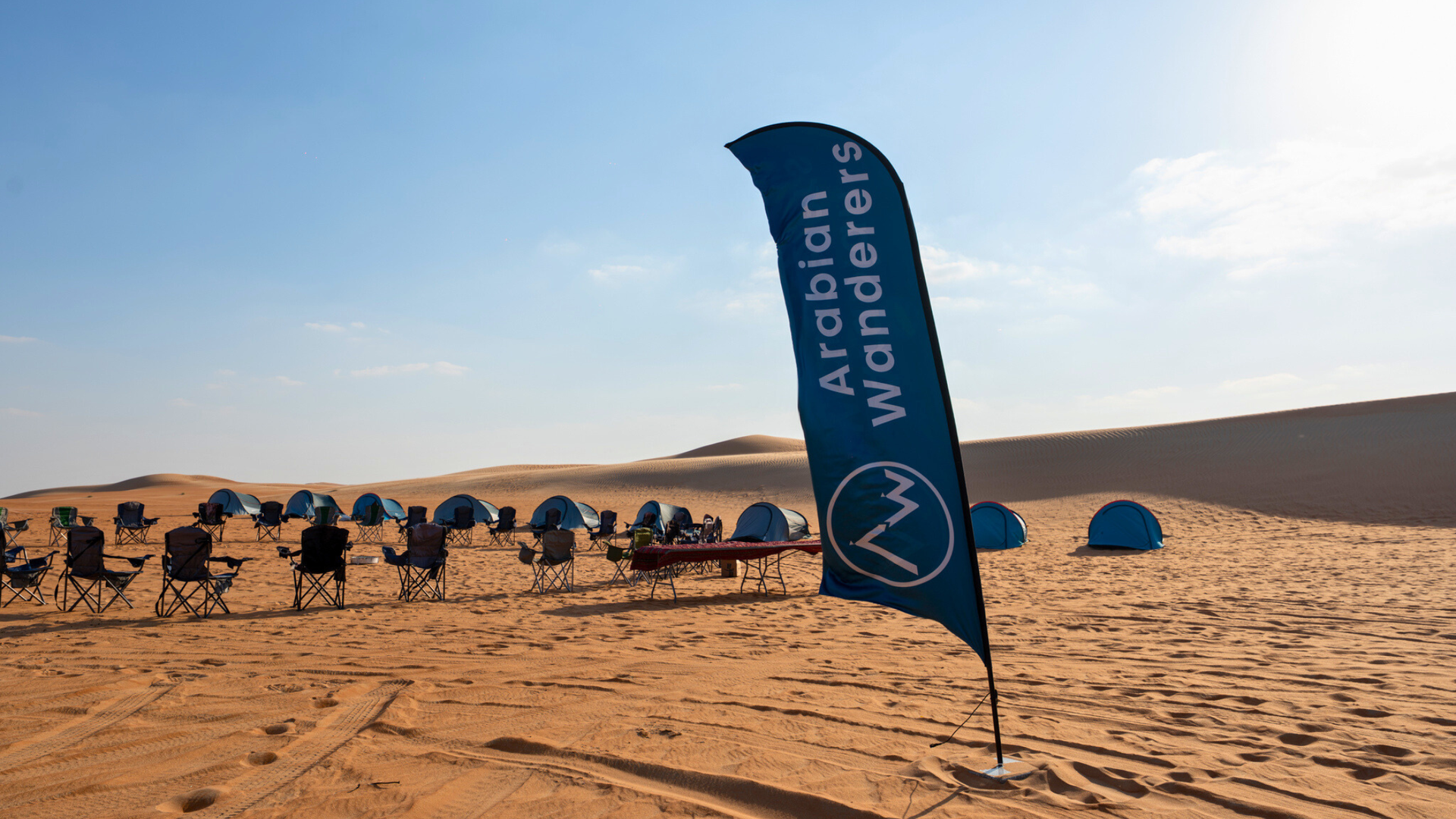 Arabian Wanderers flag and camp setup in Al Quaa desert.