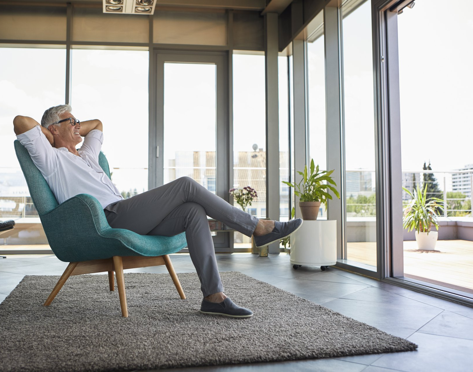 a smiling man relaxing on a chair and looking out of the window