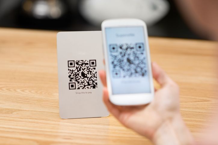 Uma pessoa está segurando um telefone celular e um código QR.