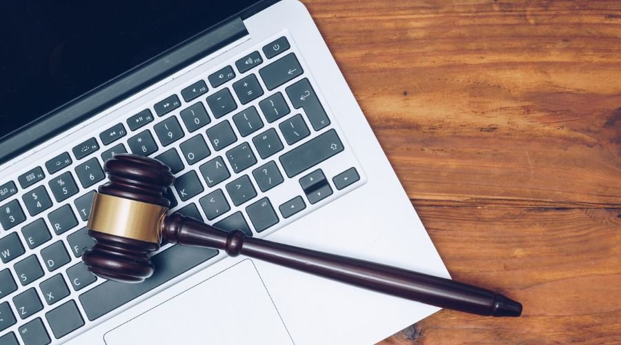 O martelo de um juiz de madeira está em cima do teclado de um laptop.