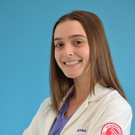 A woman wearing a lab coat with the name jenna on it