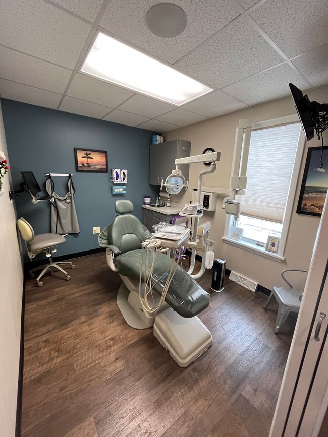 A dental office with a dental chair and a television on the wall.