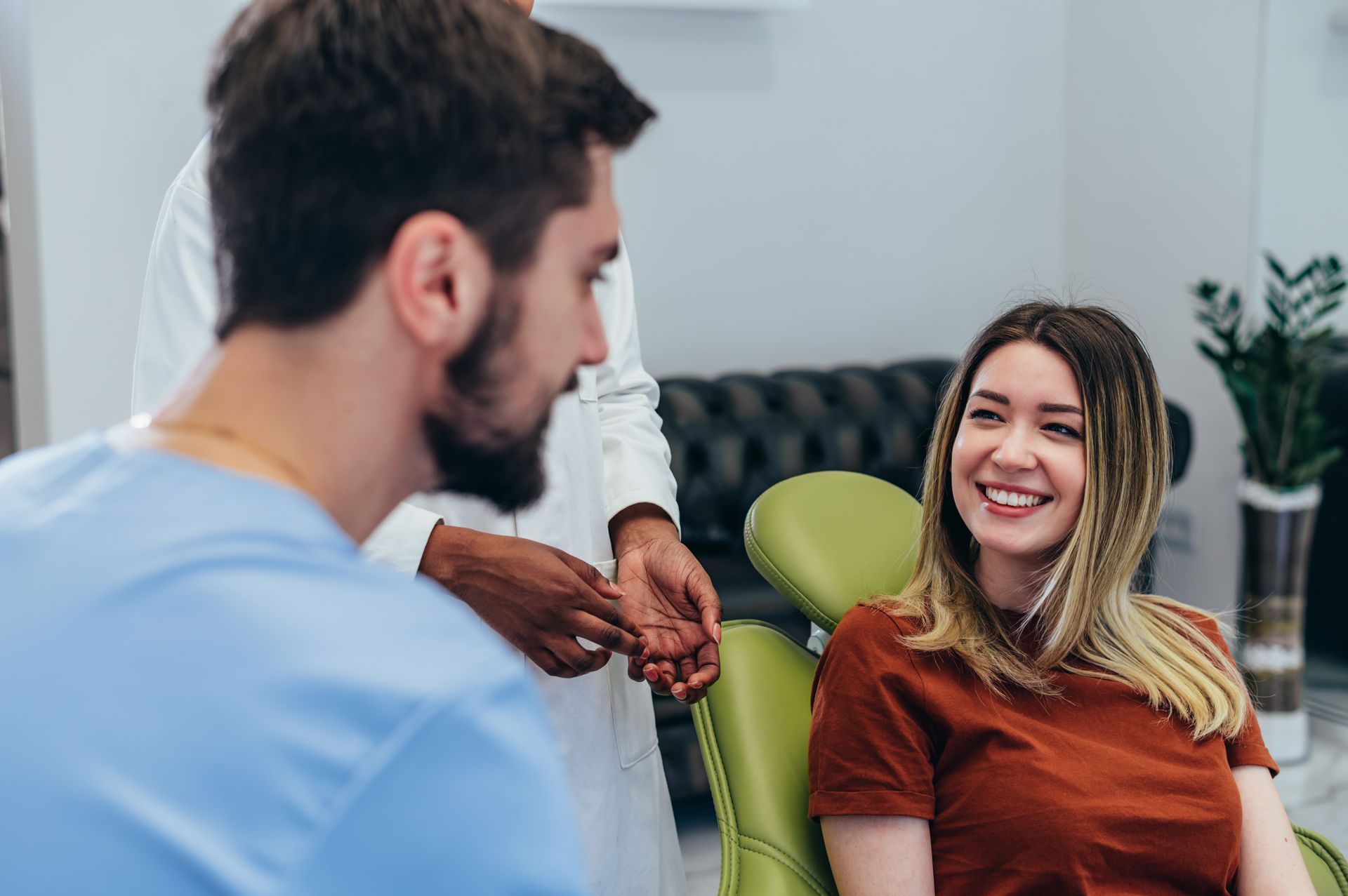 A woman is sitting in a dental chair talking to a dentist.