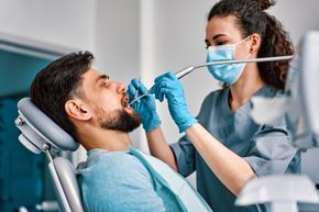 A man is getting his teeth examined by a female dentist.