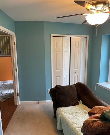 A living room with a couch and a ceiling fan.