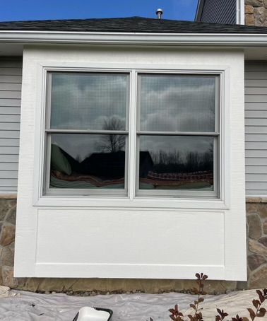 White house exterior with a four-pane window and stone siding