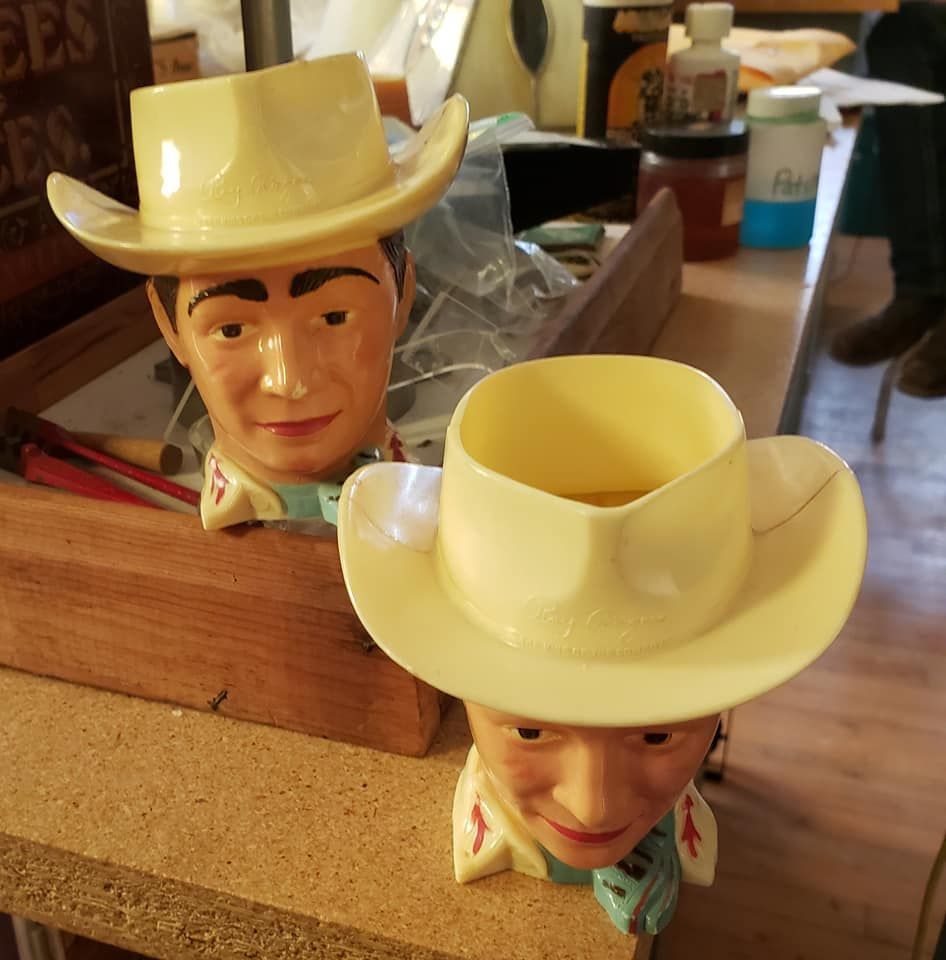 Two plastic drinking cups shaped like a cowboy's head with hat. Hat is hollow for drinking. 