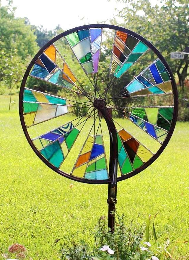 Wheel with various brightly colored stained glass pieces soldered to the spokes -Hen Picked Antiques & Stained Glass. 