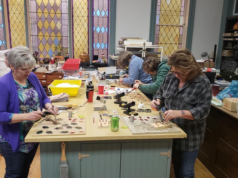 Ladies Day Out-stained glass students at a workshop table working on their projects. 