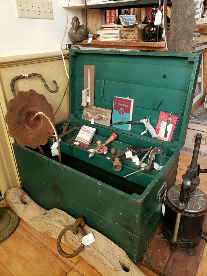 Green painted carpenter's trunk with various antique tools and books in Hen Picked Antiques.