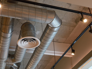 A water heater and a furnace unit with large, yellow-insulated vent pipes sitting on a raised platform in a utility room.