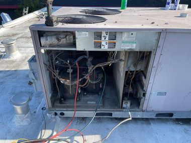 A technician using a manifold gauge set to check or service an outdoor air conditioning unit.