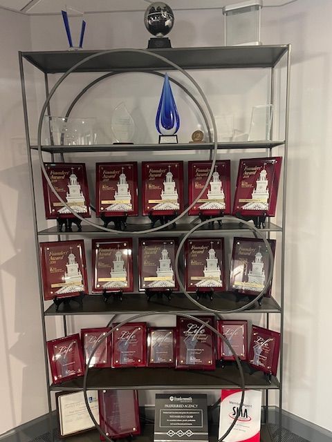 Glass shelf with rows of red plaque awards and a blue trophy centerpiece