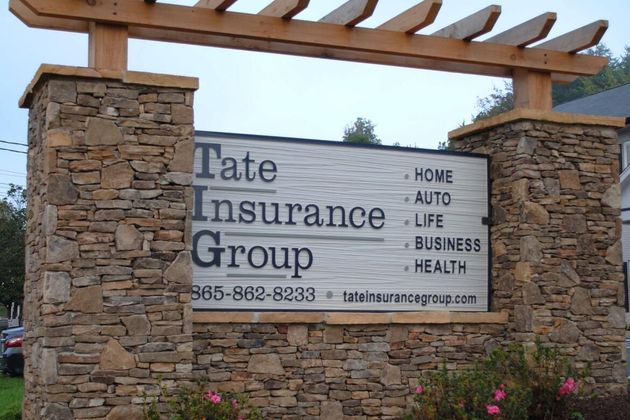 Stone monument sign for Tate Insurance Group with services listed: home, auto, life, business, health.