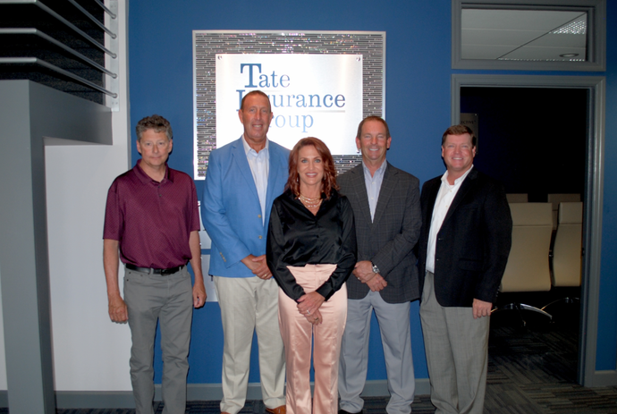 Five people posing in front of a Texas Insurance sign inside an office lobby