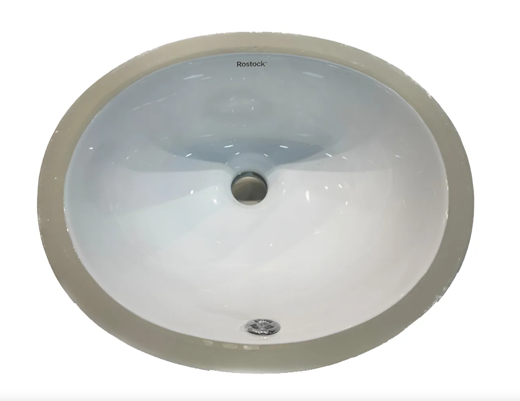 Un lavabo bajo encimera para baño de forma ovalada, de color blanco, con un desagüe central y un orificio de desbordamiento circular en la parte inferior.