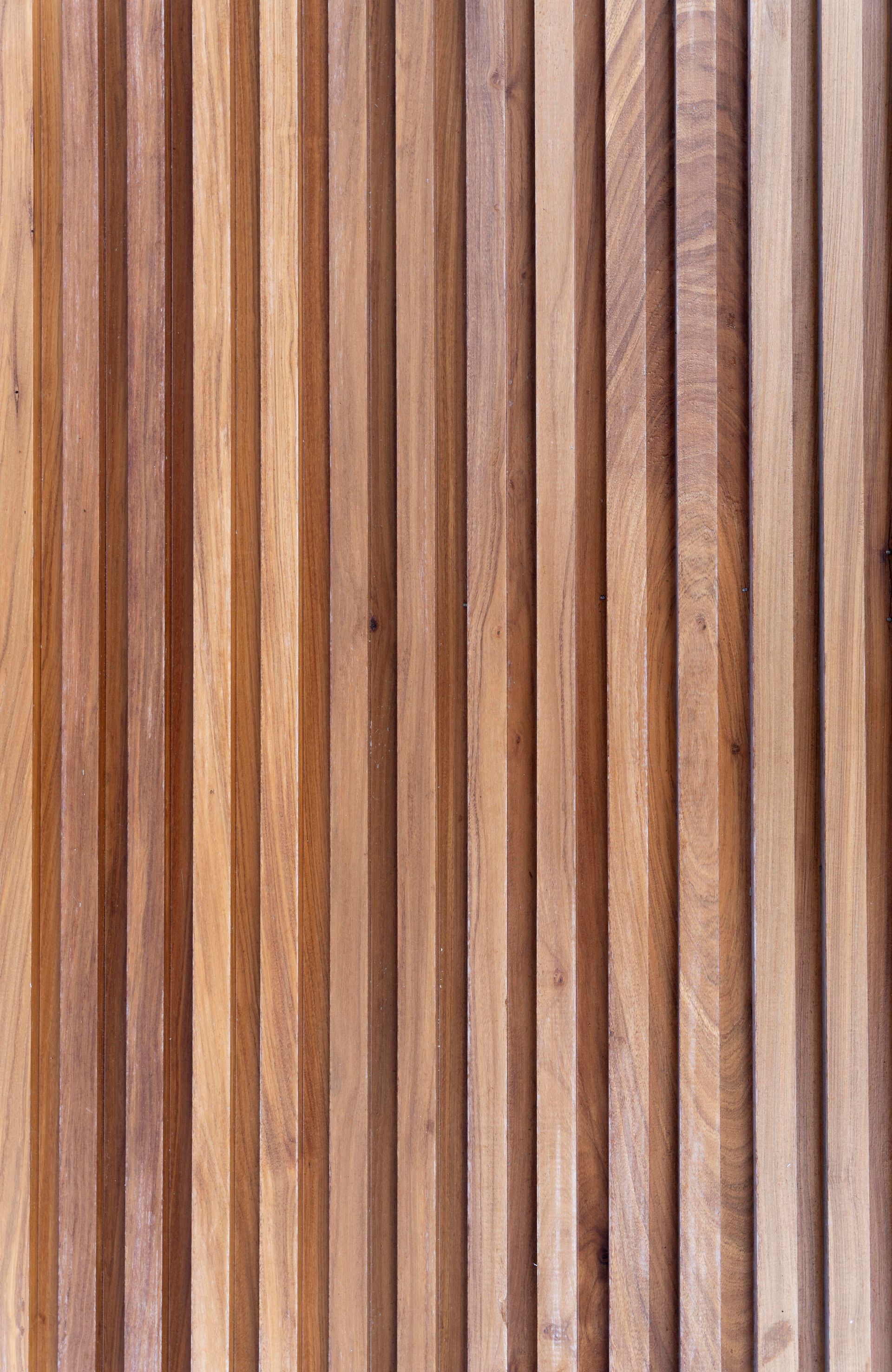 Listones de madera verticales en distintos tonos de marrón crean una superficie texturizada.