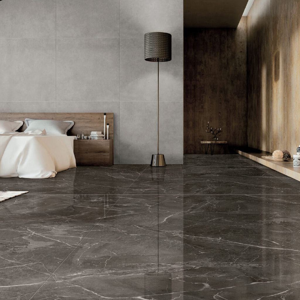 Un dormitorio moderno con piso de mármol oscuro brillante, una cama minimalista y una lámpara de pie alta contra una pared gris.