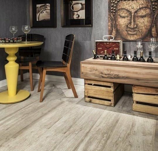 Un comedor de esquina con una mesa de pedestal amarilla, sillas de madera y una consola de madera rústica hecha con cajas.