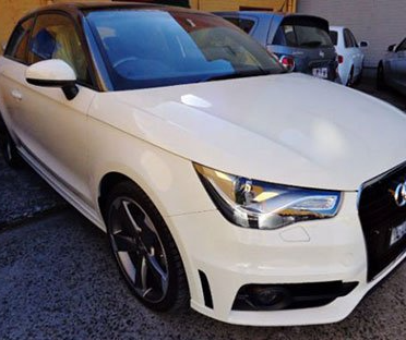 A white audi a1 is parked in a parking lot