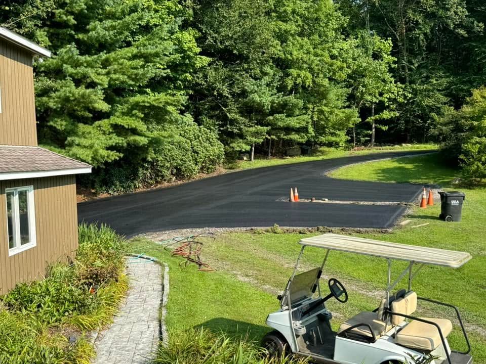 Blacktop parking lot beside a tan building and green trees, with a golf cart in the foreground.