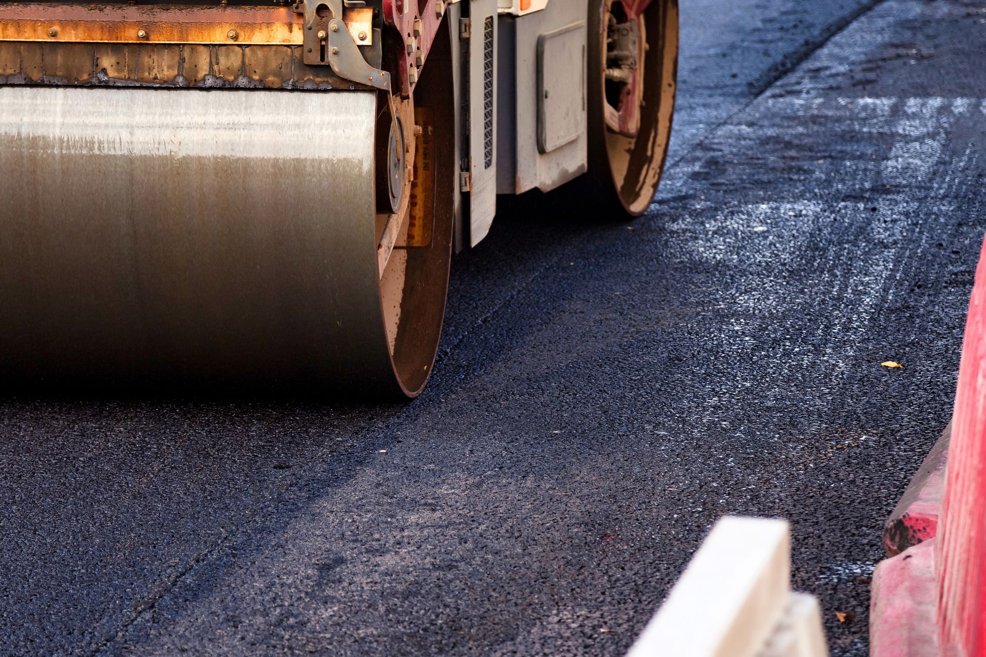 Road roller compacting fresh asphalt on a street construction site.