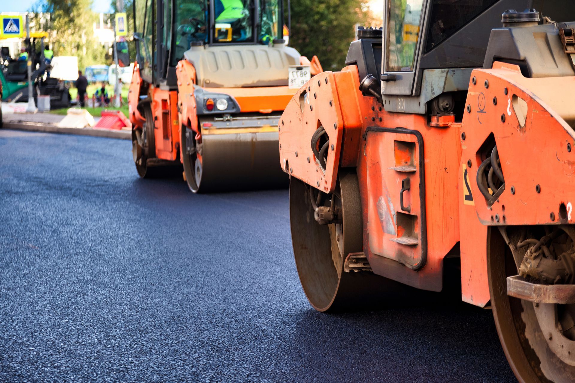 Orange road rollers paving a freshly laid asphalt street.