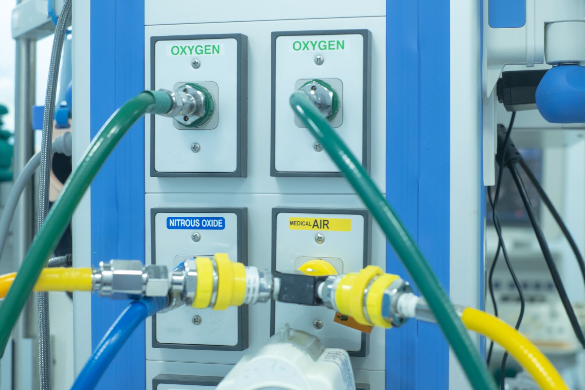 Industrial gas control panel with oxygen and mixed-gas hoses connected to labeled valves and outlets