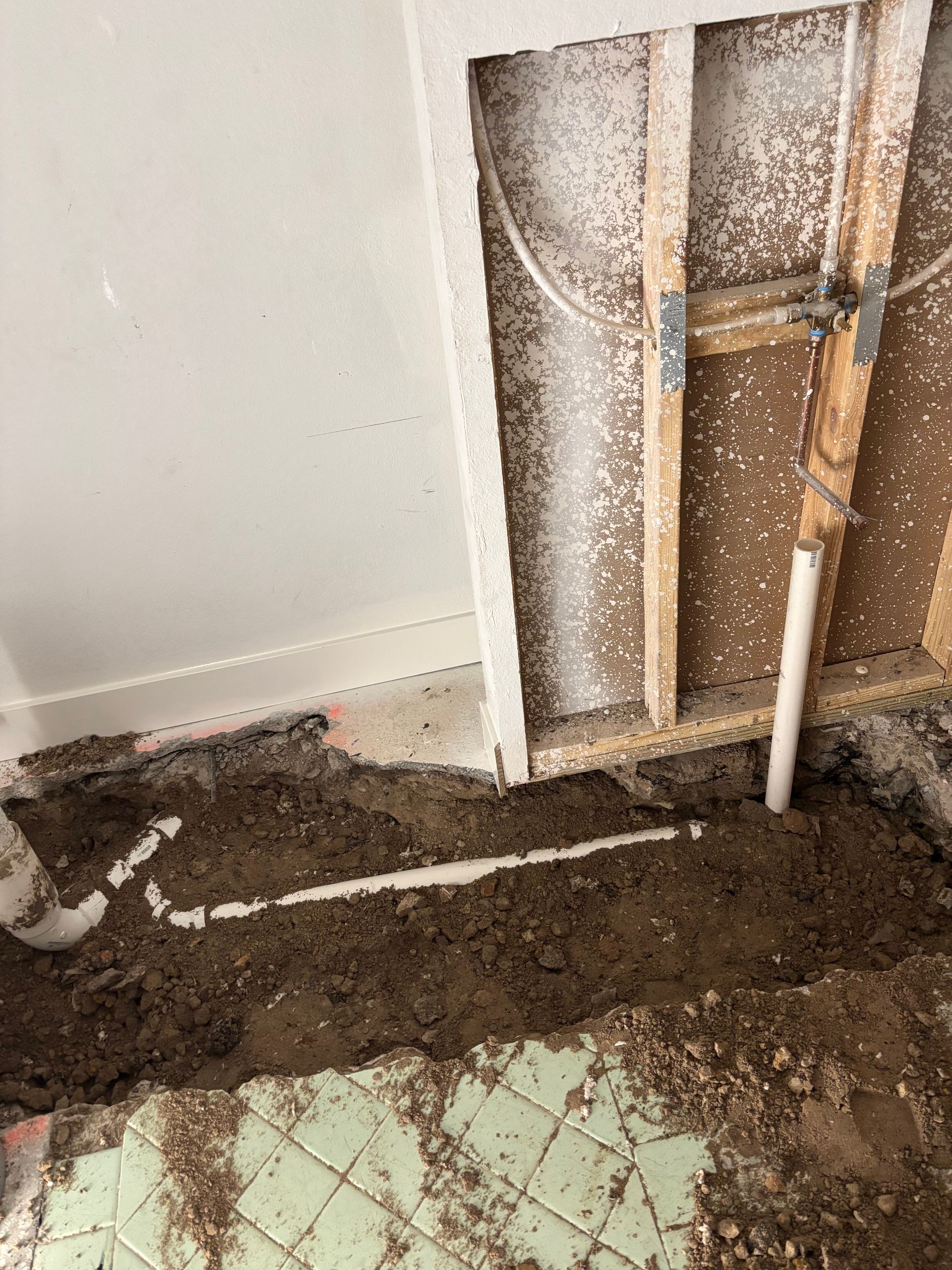 Worker installing orange PVC pipes at a construction site