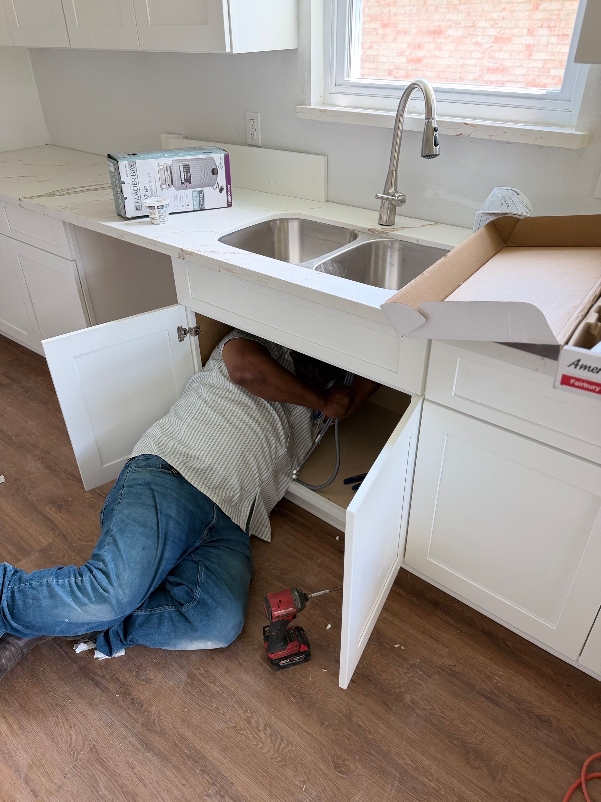 Plumber inspecting under-sink pipes in a modern kitchen cabinet