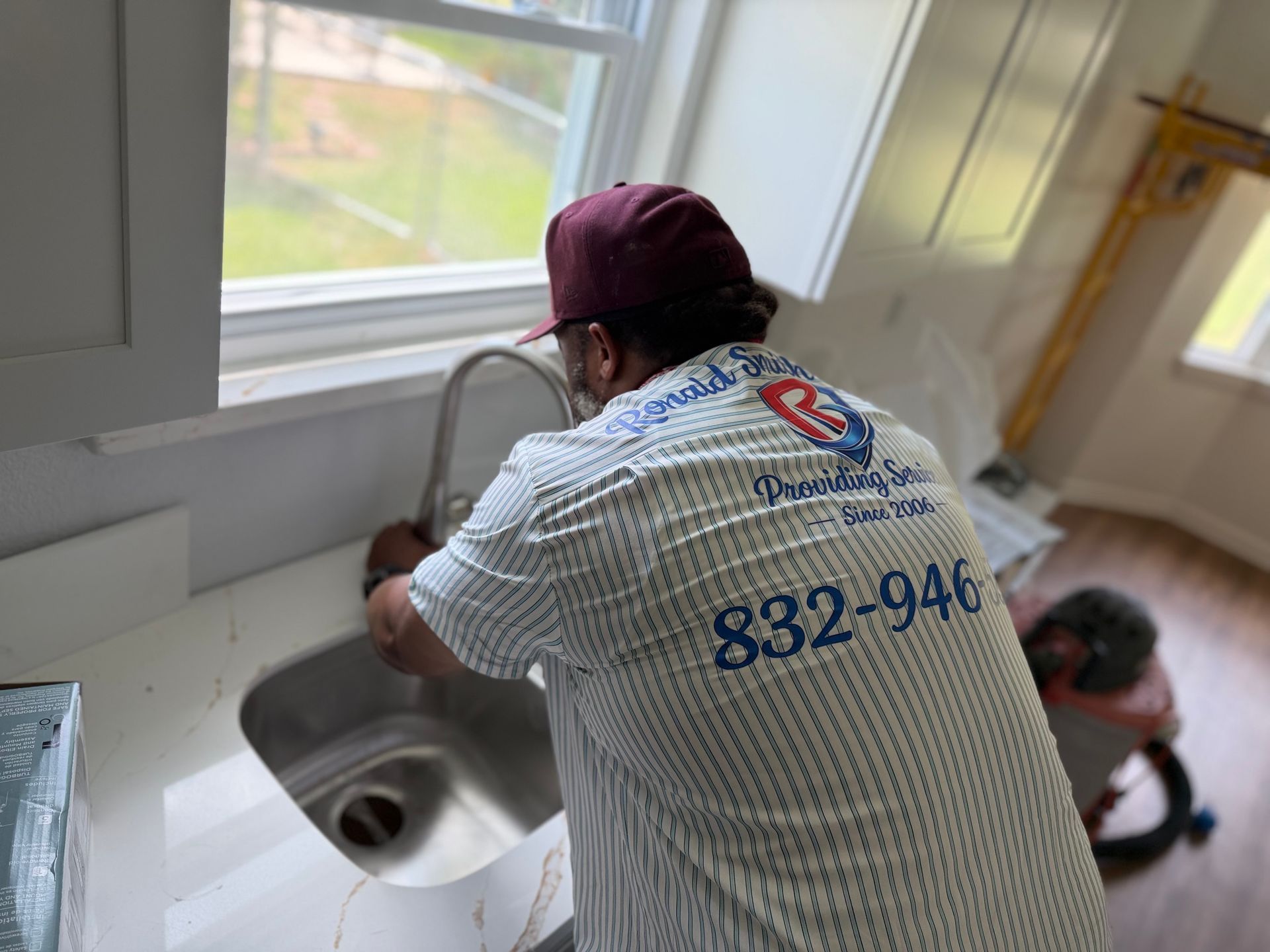 Person fixing a bathroom sink with wrenches and screwdriver on a white countertop
