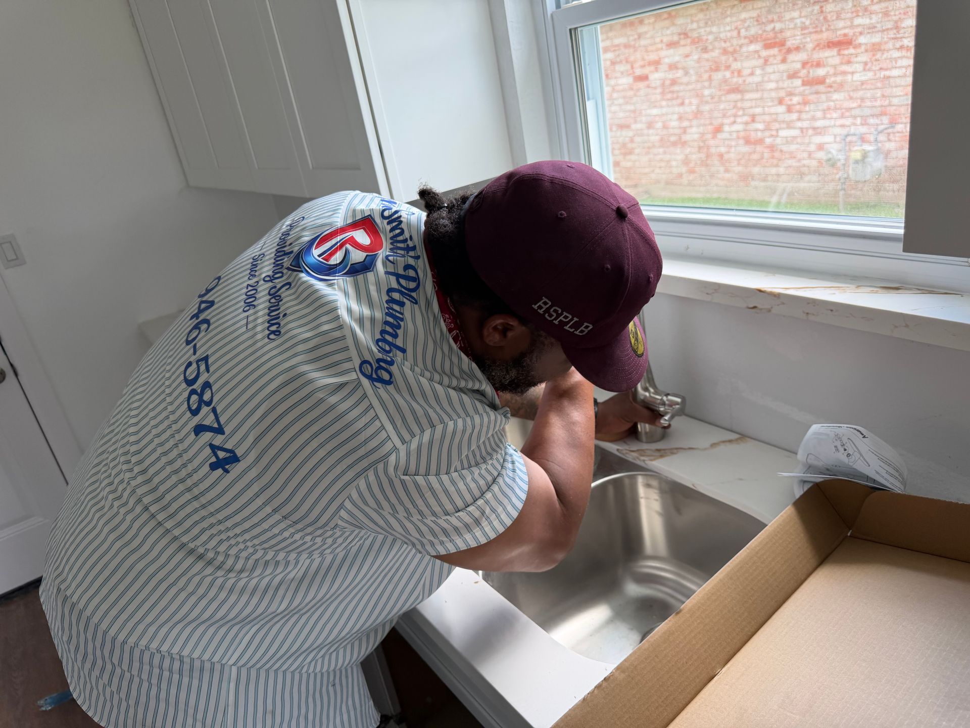 Plumber installing a wall pipe fitting near a concrete block wall using a wrench