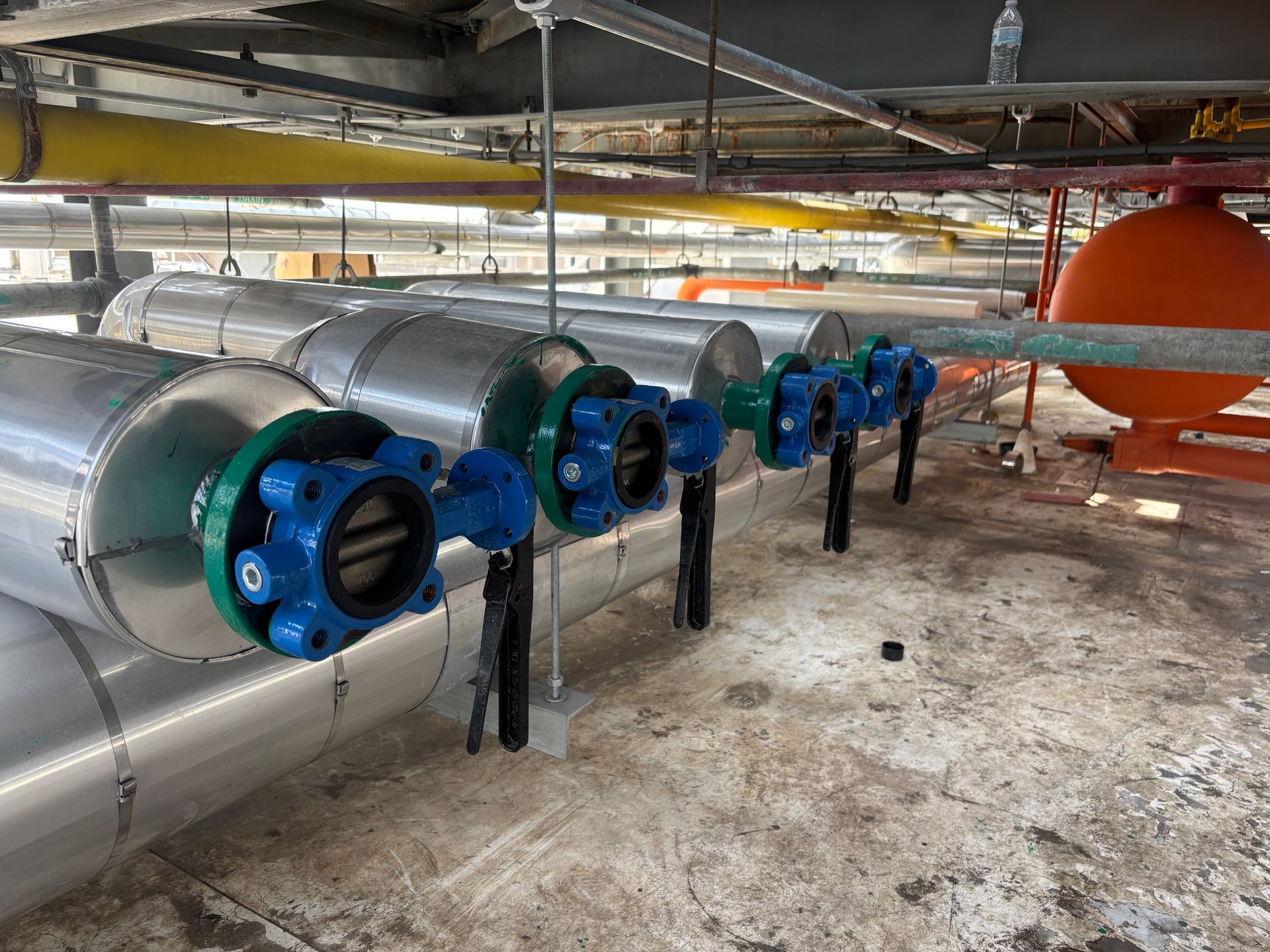 Ceiling with blue and black industrial pipes and ducts in a mechanical room